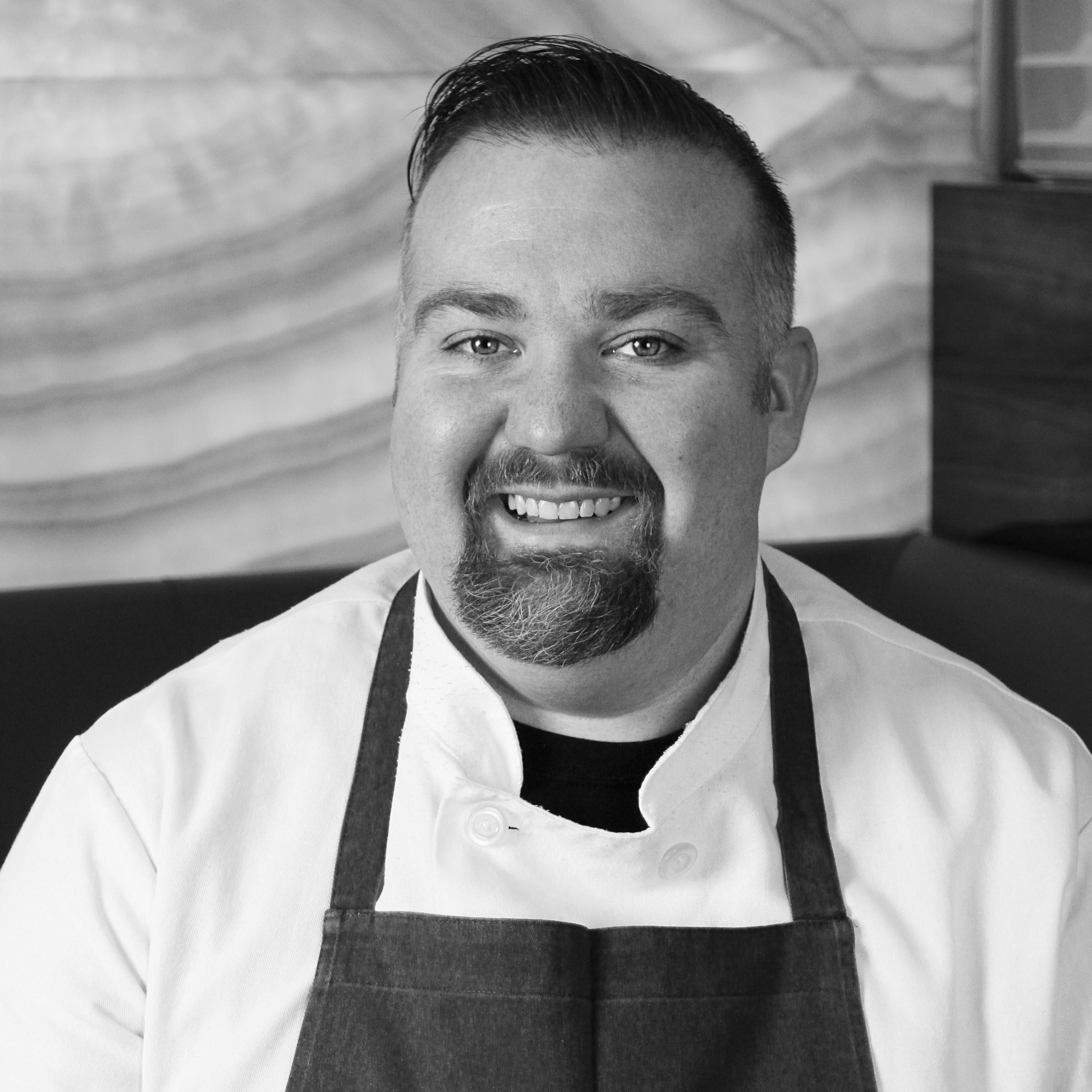 headshot of a man in a chef's coat and apron